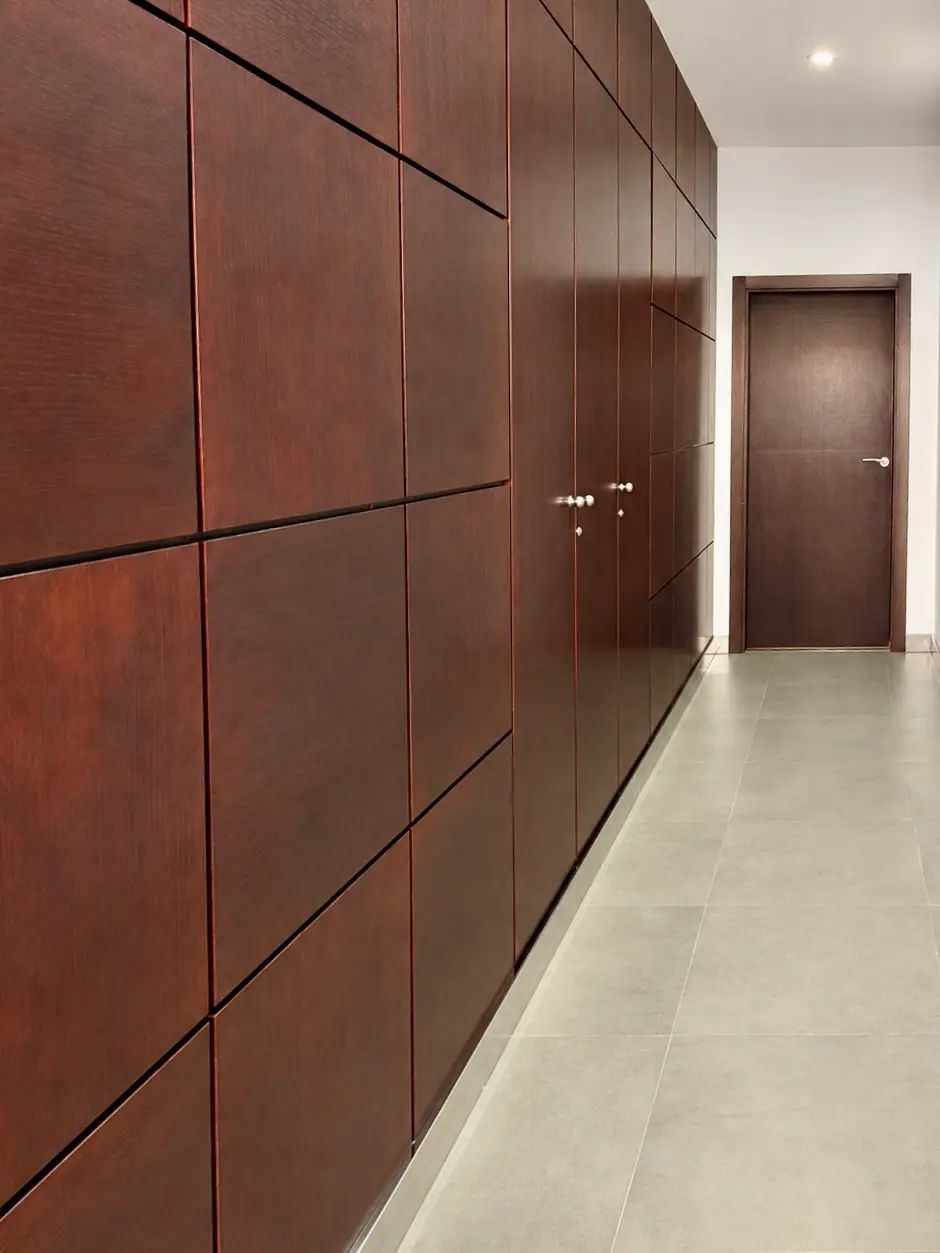 Corridor at the centre, lined with dark wood panels leading to the consulting rooms.